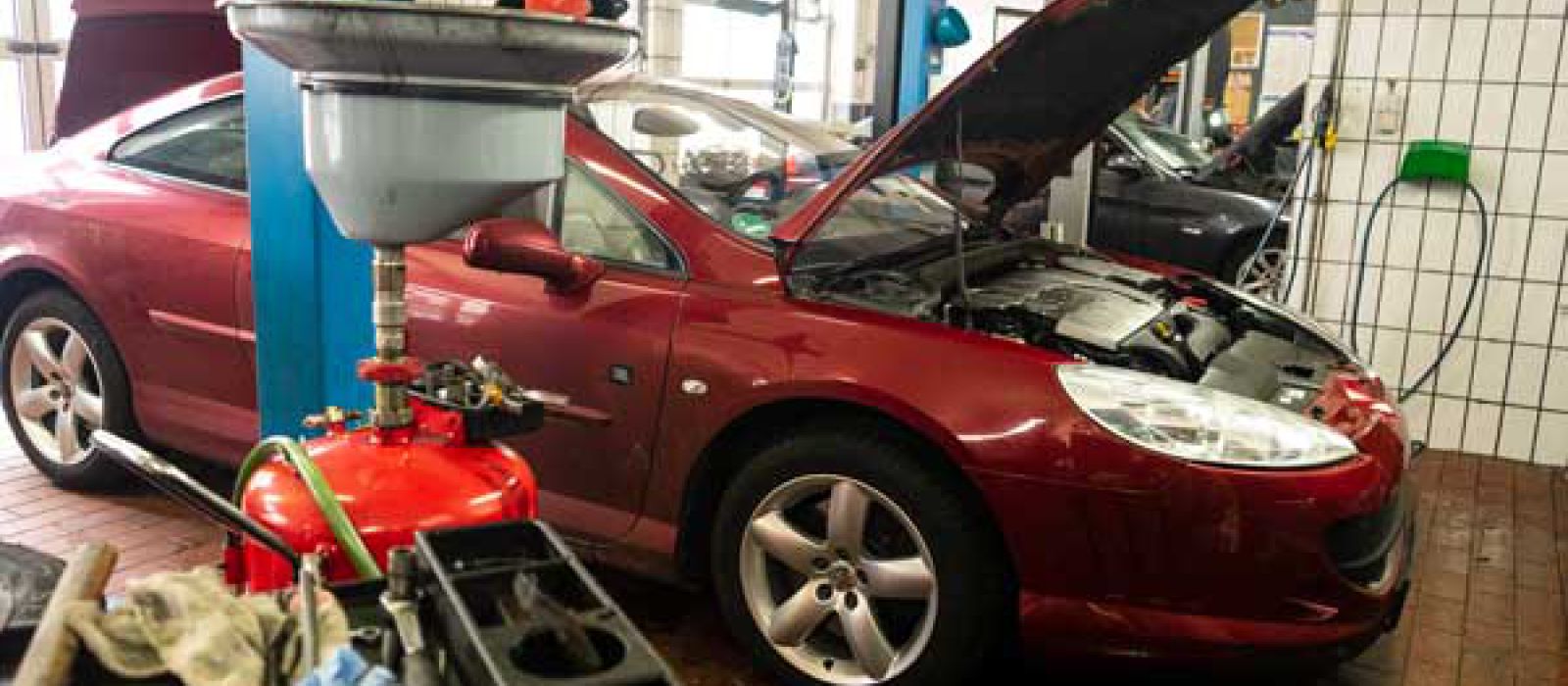 Rotes Auto in Werkstatt mit offener Motorhaube